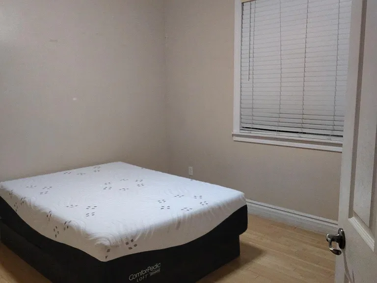 Private bedroom with wood-style flooring, ceiling fan, and a window with blinds for comfortable everyday living.