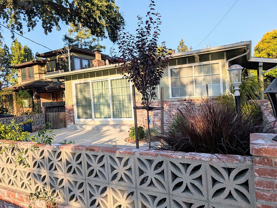Patio fenced with butterfly bricks, greenery.