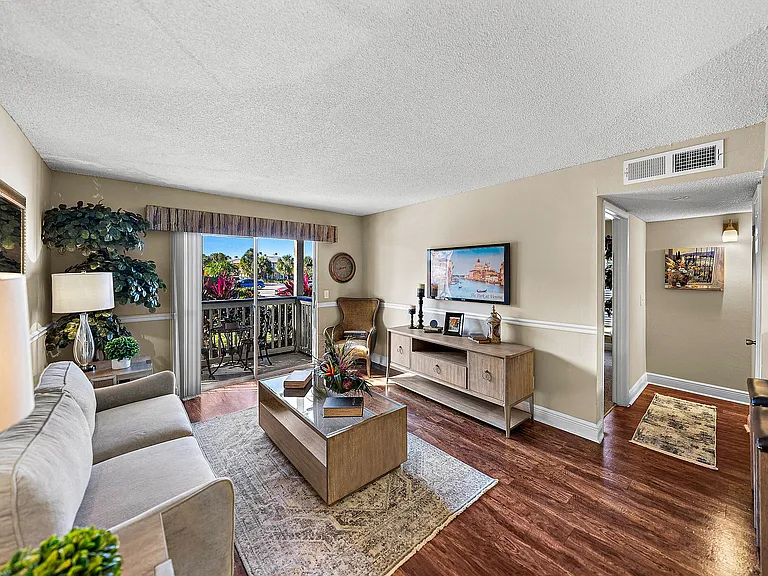Spacious living room with wood-style flooring and sliding glass doors leading to a private patio.
