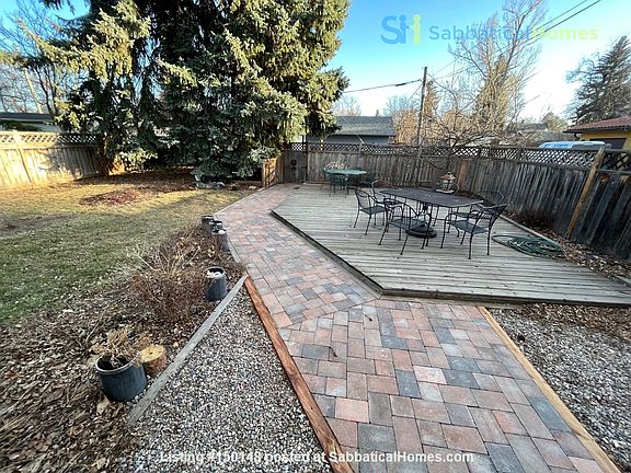Backyard with deck and outdoor seating at two tables for 10 ppl