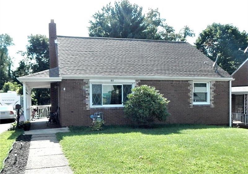 BRICK CAPE COD HOME WITH A COVERED SIDE PORCH.