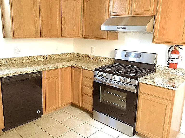 Kitchen has granite countertops, tile floor, gas stove with range, dishwasher, garbage disposal, refrigerator. There's plenty of cabinet space.