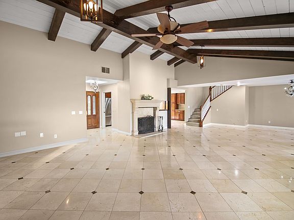 Entry to grand living room with travertine flooring and beamed ceilings.