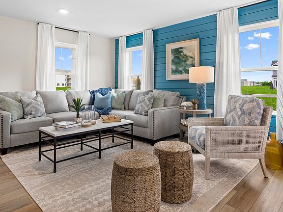 Living room with seating and 3 large windows in a DRB Homes Whitehall Model at the Village of Colleg