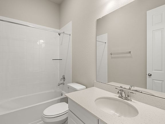 The secondary bath features tile flooring, white cabinetry and light countertops and a shower tub co