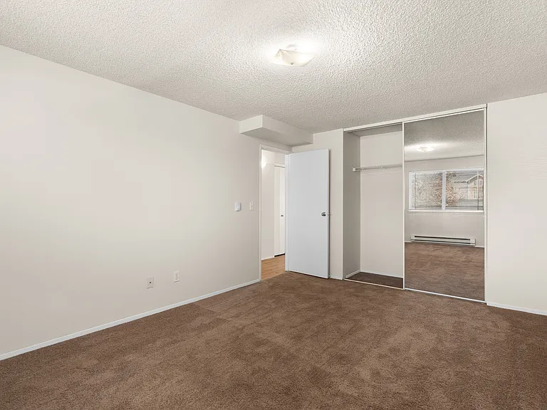 Spacious bedroom with plush carpet, mirrored closet doors, and ample natural light. Spacious bedroom with plush carpet, mirrored closet doors, and ample natural light.