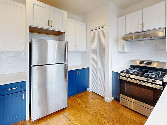 Kitchen with cabinets, refrigerator, stove, range hood, and sink
