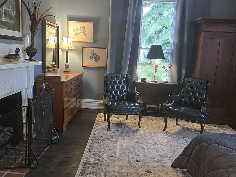 Second bedroom from hallway entrance. Original fire place; dresser and Kentucky artwork featured (Alan Brewer and Joseph Petro); sitting area and vintage wardrobe for ample storage. Ceiling fan.