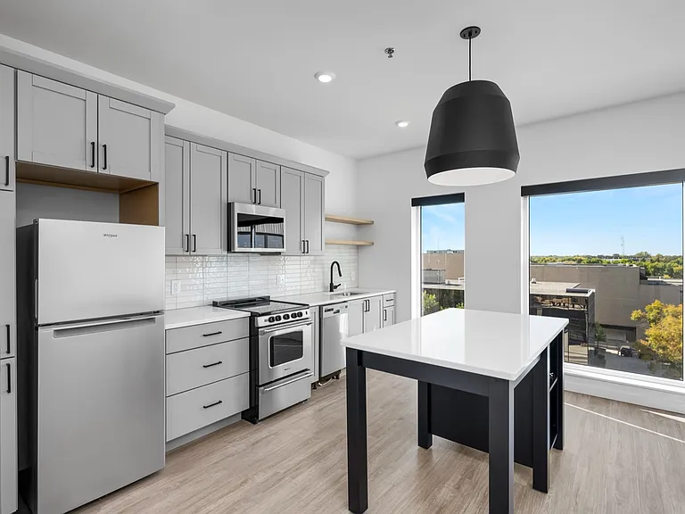 Bright and modern kitchen featuring sleek gray cabinetry, a stainless steel refrigerator, and a spacious island, with large windows offering scenic views. Bright and modern kitchen featuring sleek gray cabinetry, a stainless steel refrigerator, and a spac