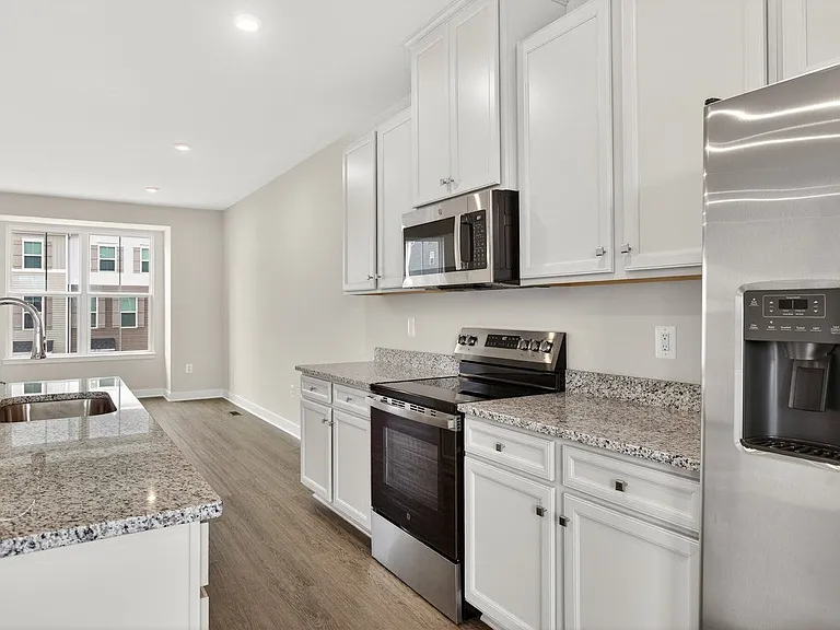 closer view of the kitchen along the wall; stainless steel range & microwave, granite countertops