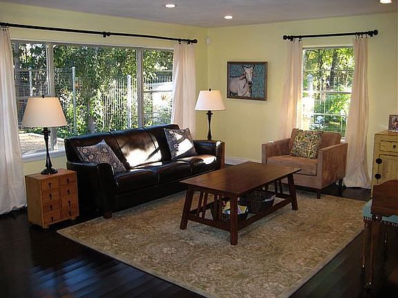 The living room has large windows that look out into the back yard.