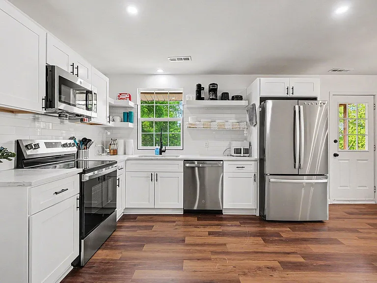 Updated kitchen with ample white cabinetry, stainless steel appliances, and a window over the sink for everyday prep.