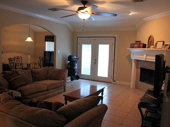 SPACIOUS LIVING ROOM WITH WOOD BURNING CHIMNEY, CEILING FAN, TILE FLOOR, CROWN MOLDING, FRENCH DOORS