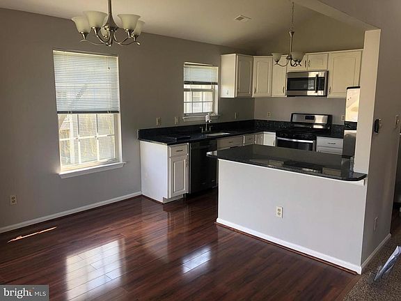 kitchen with stainless appliances with gas cooker, granite counters and hardwood flooring in the eat in/dining area
