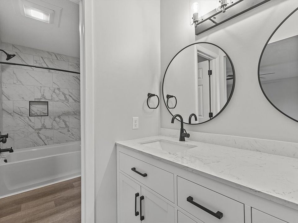 Primary bathroom with tiled tub surround, double vanity with quartz counters