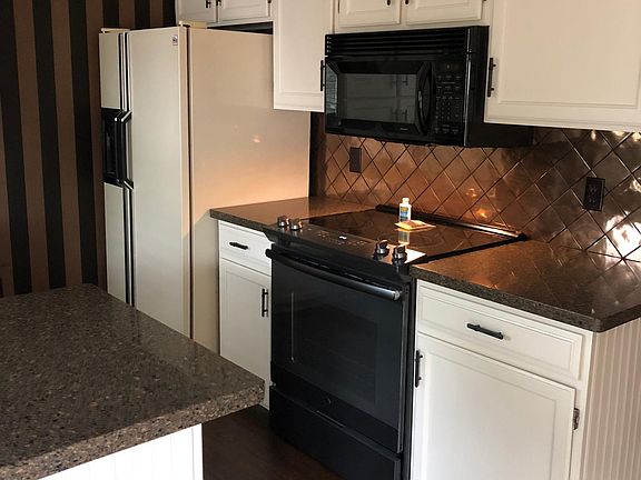 Kitchen showing granite counters, new stove/oven, microwave and refrigerator