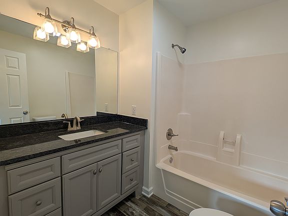 Fully renovated master bath complete with new vanity and granite countertop, new toilet, and new lighting.