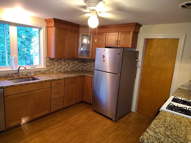 Kitchen showing gas stove, stainless steel refrigerator, wooden cabinets, ceiling fan.