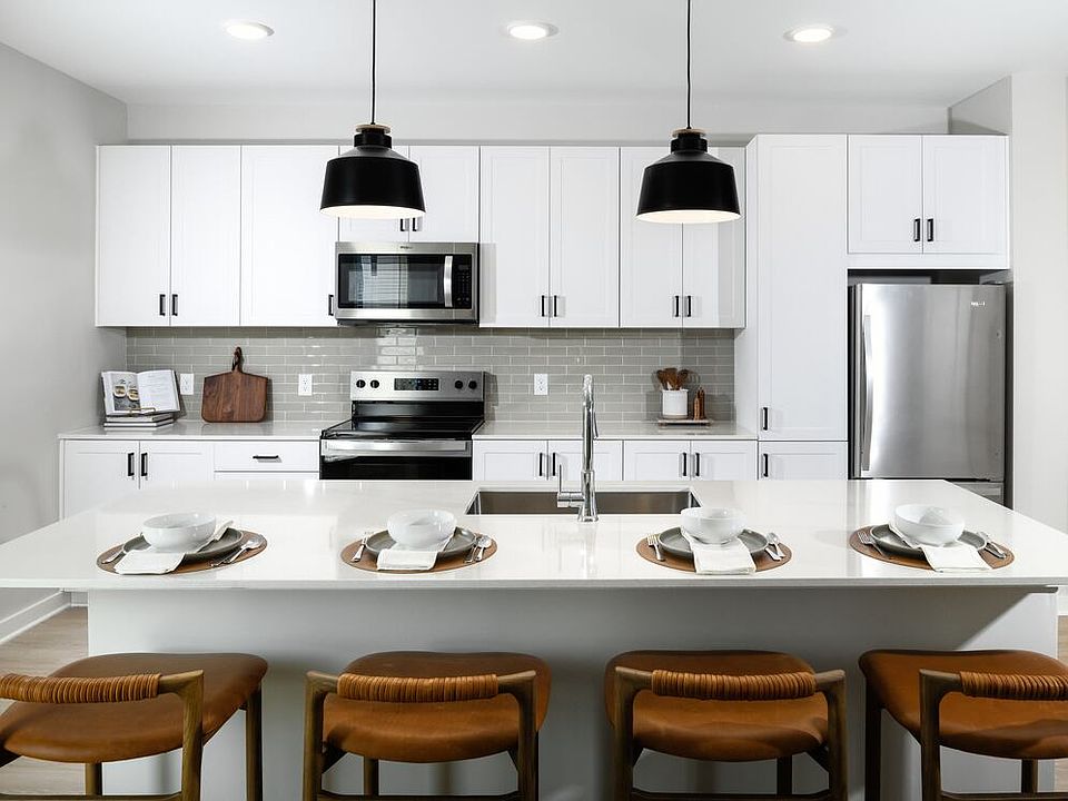 Kitchen with white shaker cabinetry, white quartz countertops, grey tile backsplash, and stainless steel appliances