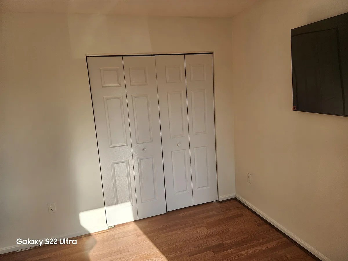 Bedroom with wood-look flooring and a sliding-door closet for convenient storage and easy organization. - Crandall Rd