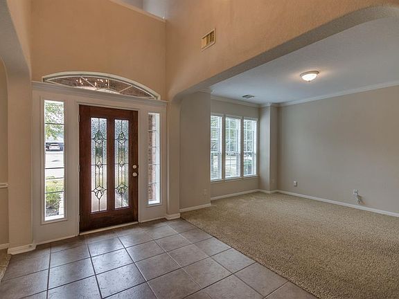 Stunning foyer with high ceilings, crown molding, gorgeous leaded glass and wood door & beautiful lighting.