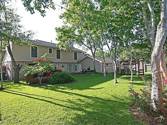 Gorgeous backyard with trees, deck, and playset.