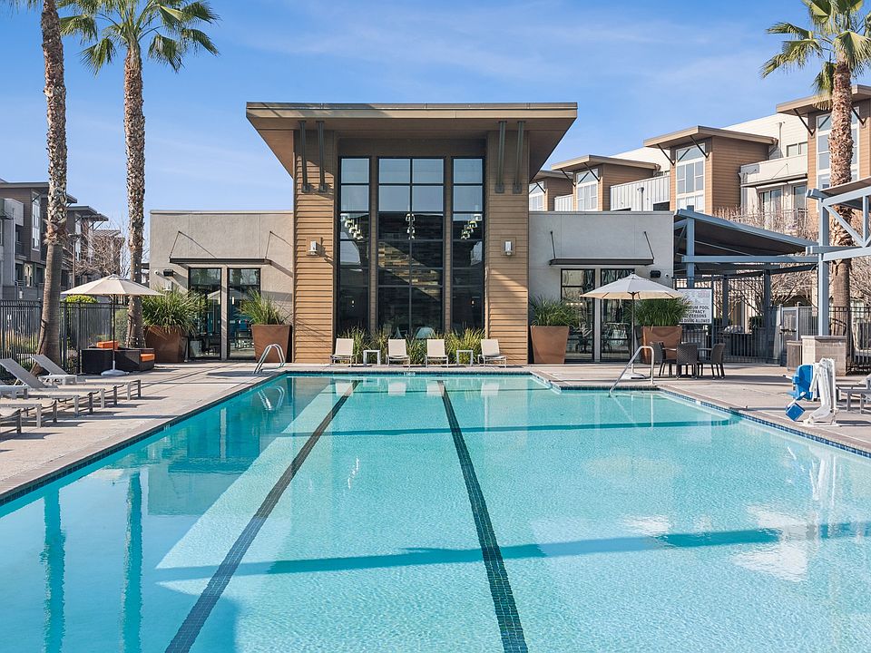 Aspire Apartments Tracy California Luxury Living A large swimming pool in front of a building with palm trees.