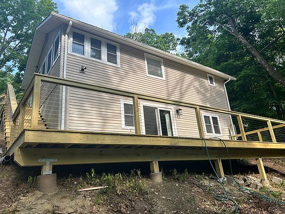 Back view of home with deck overlooking brook & lake