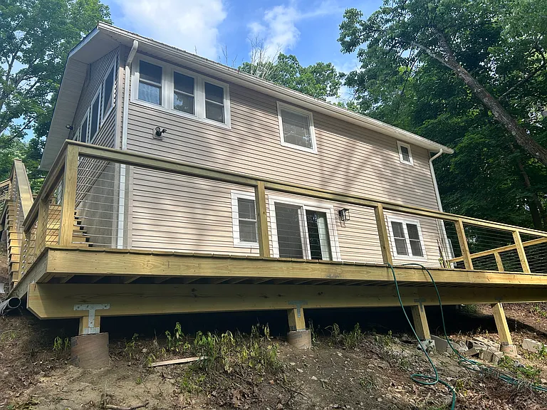 Back view of home with deck overlooking brook & lake