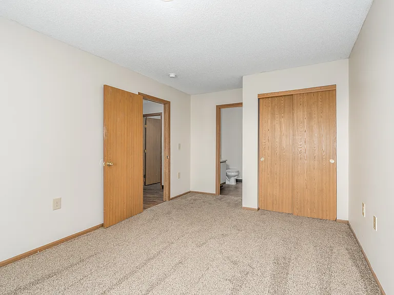 Carpeted bedroom, closet, and attached bathroom of a River Valley apartment home in Lancaster, OH.