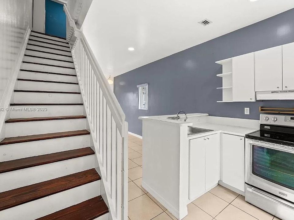 Entrance: Features a view of the stairs and kitchen to the right, with impressive high ceilings.