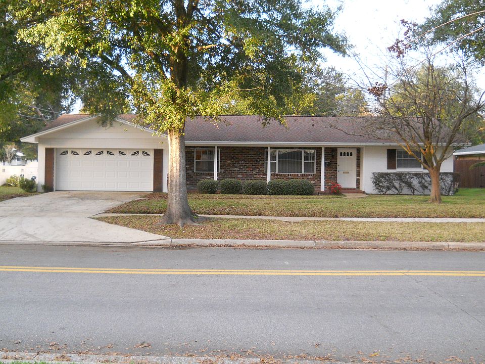 Colonial style home with front porch, with space for small table and chairs and plants in pots.
