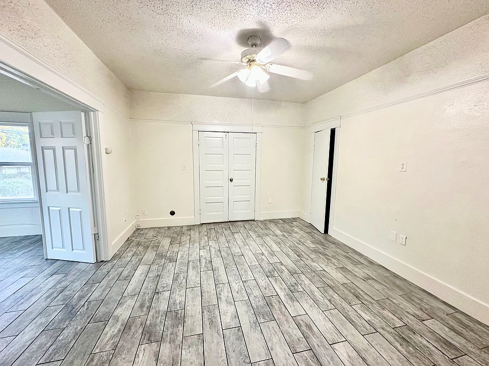 Spacious living room with ceiling fan and double door entrance to huge bedroom.