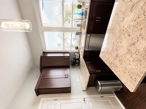 Kitchen with granite counters, dark cabinetry, and a large window over the sink for comfortable meal prep and cleanup.