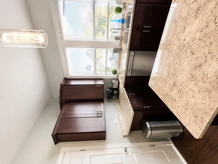Kitchen with granite counters, dark cabinetry, and a large window over the sink for comfortable meal prep and cleanup.