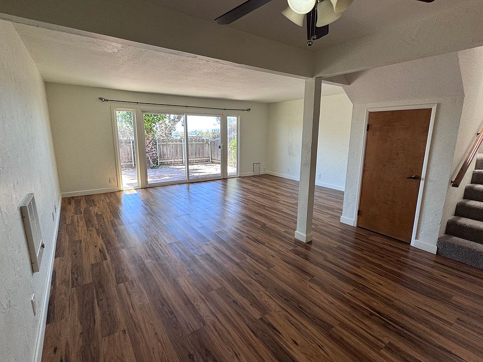 Spacious living room showing large glass sliders to the patio, storage under the stairs. Wall heater heats up the house quickly when needed.