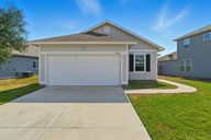 Front elevation of 1905 Estes Flats Dr, Aransas Pass, TX modern coastal façade with covered entry, two car garage, wide driveway, and manicured lawn.