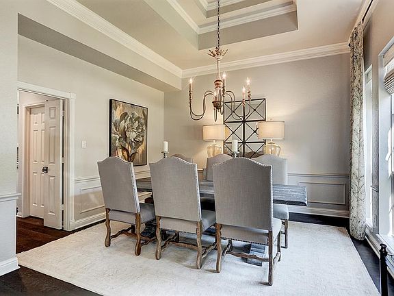 Chair rail, frame molding, crown molding and a tray ceiling decorate this beautiful formal dining room. Natural woven shades cover the windows.