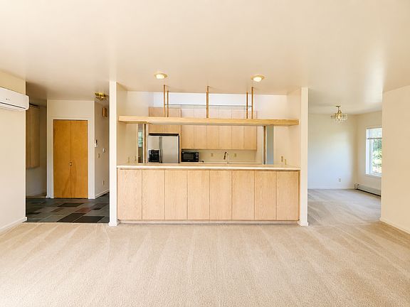 This is a view from the wall of windows in the living room. You look directly into the kitchen - notice all the storage cabinets in the living area, too - with the dining room to the right and the entryway and hallway to the rest of the unit to the left.