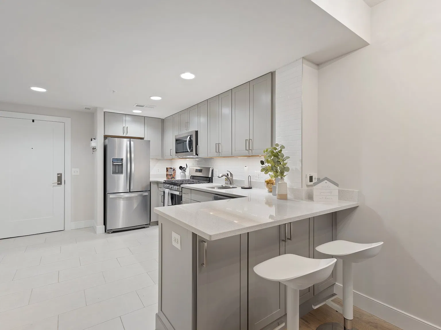 All new kitchen with white subway tile backsplash and task lighting, with breakfast bar