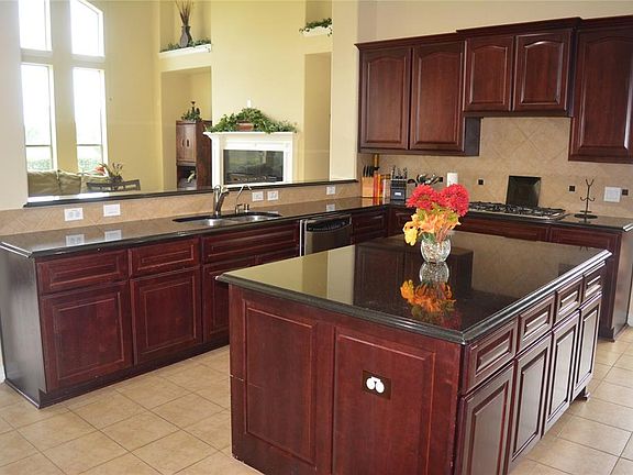 Kitchen overlooking the family room complete with granite countertops, tile granite backsplash, and tile flooring. All appliances stay w/the home.
