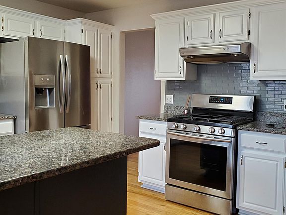 Large gas stove with new tile backsplash. Hardwood floors.