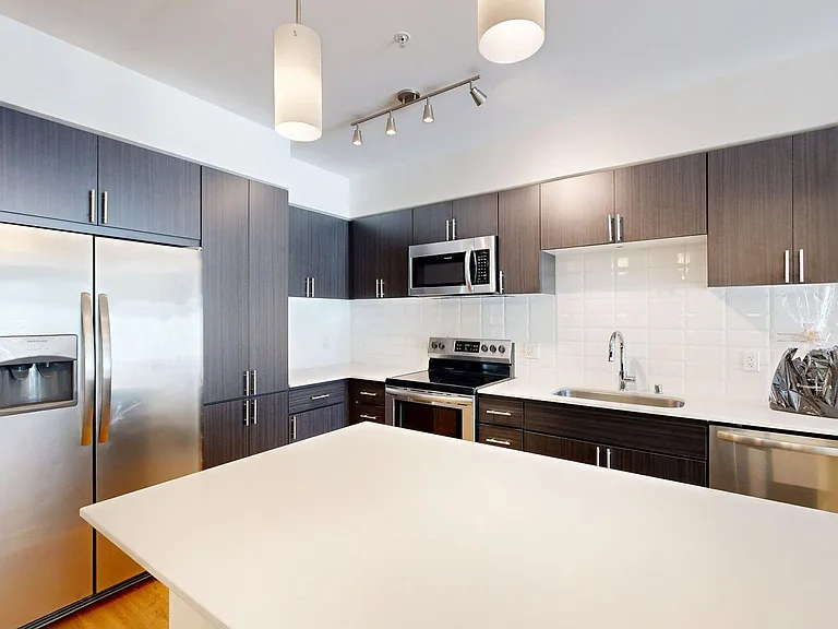 Apartment Kitchen with Stainless Steel Appliances, Dining and Living Room with Wood-Style Flooring.