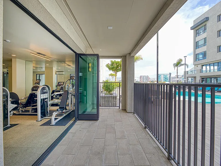 Fitness center with a covered patio and open views connecting indoor workouts to the pool deck.
