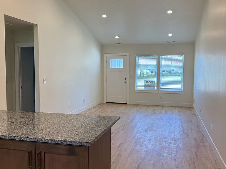 A beautifully finished living space with large windows bringing in natural light, complemented by a beautiful rustic beam and modern ceiling fan.