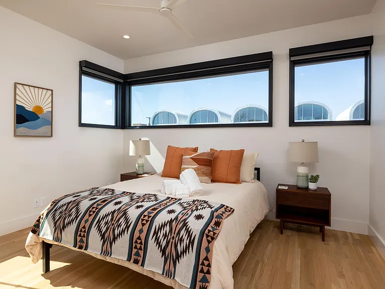 Bedroom 2 features a queen bed and windows on two sides, with room-darkening shades for restful sleep and added privacy.