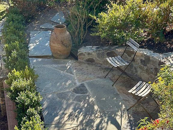Stone steps wind through the hillside garden, ending in the sunny patio seating area, as shown in this aerial view.