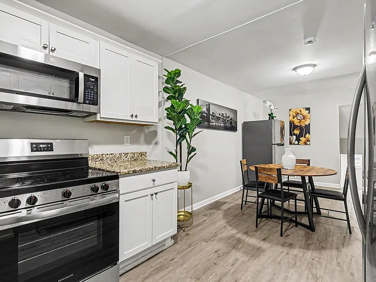 Kitchen features white shaker cabinetry, granite-look counters, and stainless appliances with an adjacent dining nook.