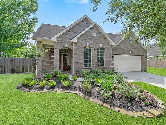 Attractive front elevation with full brick detail, perfectly manicured landscaping, and a 2-car garage.