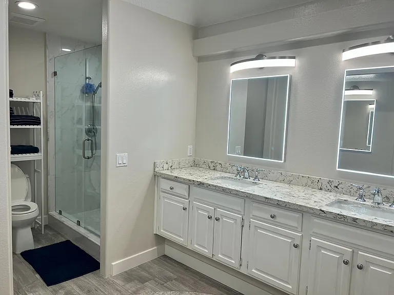 Primary bathroom with a frameless shower door and storage shelves